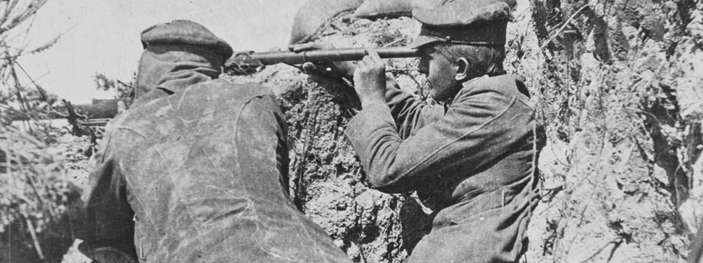 A sniper team - one soldier holds a rifle and the other a periscope